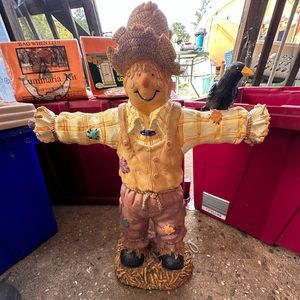 Scare crow statue with a crow on arm